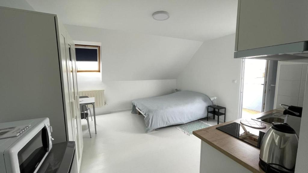 Cette petite chambre blanche dispose d'un lit et d'une cuisine. dans l'établissement Studio indépendant clair et calme, à Lannion