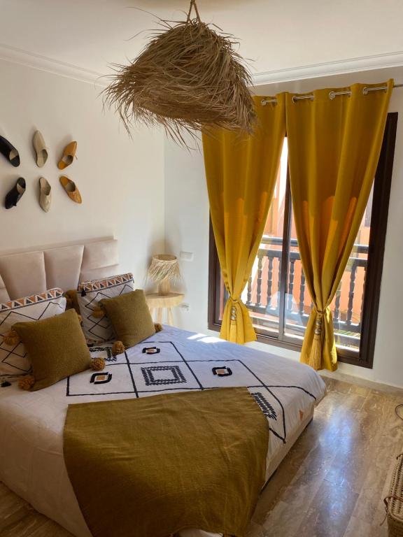 a bedroom with a bed with yellow curtains and a window at Bel appartement au centre gueliz in Marrakesh