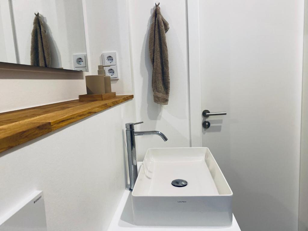 een witte badkamer met een wastafel en een deur bij Lay-Zeit in Kottenheim