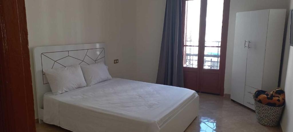 białe łóżko w pokoju z oknem w obiekcie Appartement Néoclassique centre-ville w mieście Casablanca
