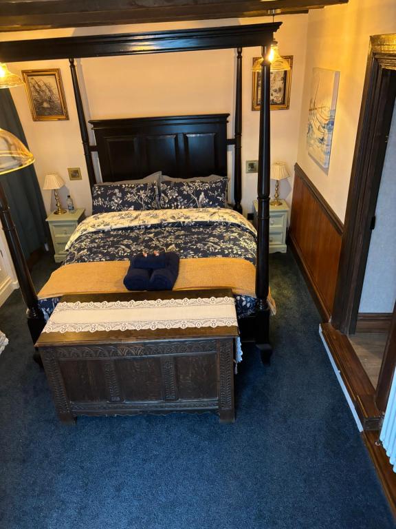 ein Schlafzimmer mit einem großen Bett mit einem Holzrahmen in der Unterkunft Captain's Nook, Luxurious Victorian Apartment with Four Poster Bed and Private Parking only 8 minutes walk to the Historic Harbour in Brixham