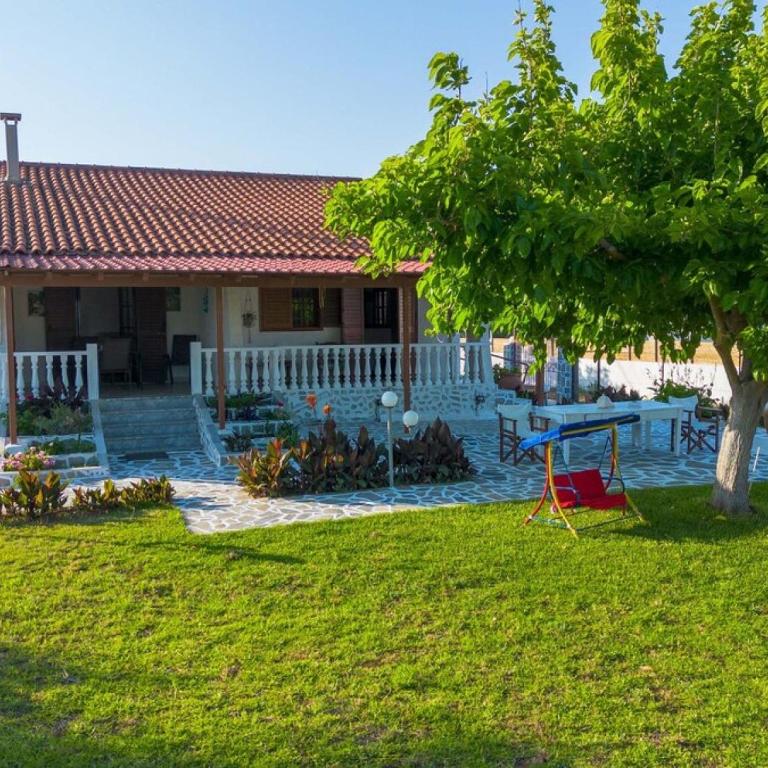 una casa con un patio con una mesa de picnic y un árbol en Seaside Retreat for Families and Pets, en Messini