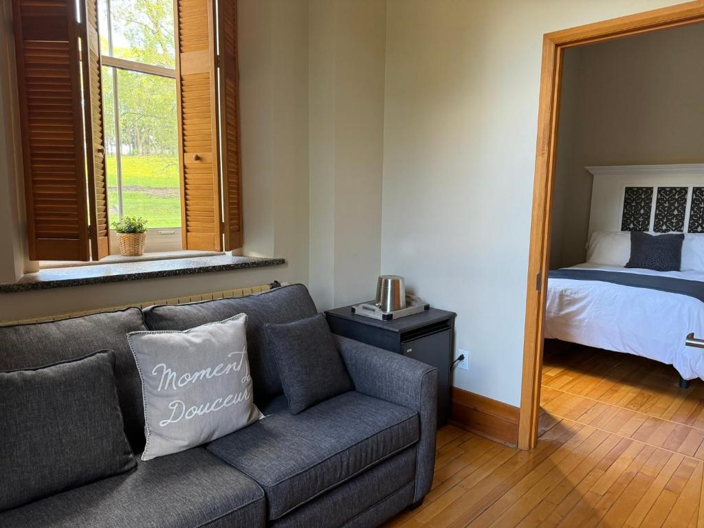 een woonkamer met een bank en een bed bij Auberge de l'Abbaye d'Oka in Oka