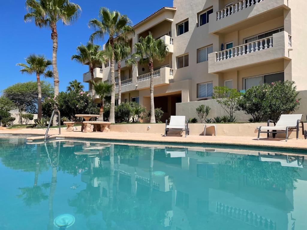a swimming pool in front of a building with palm trees at Corona del Mar By Rocky Host in Puerto Peñasco