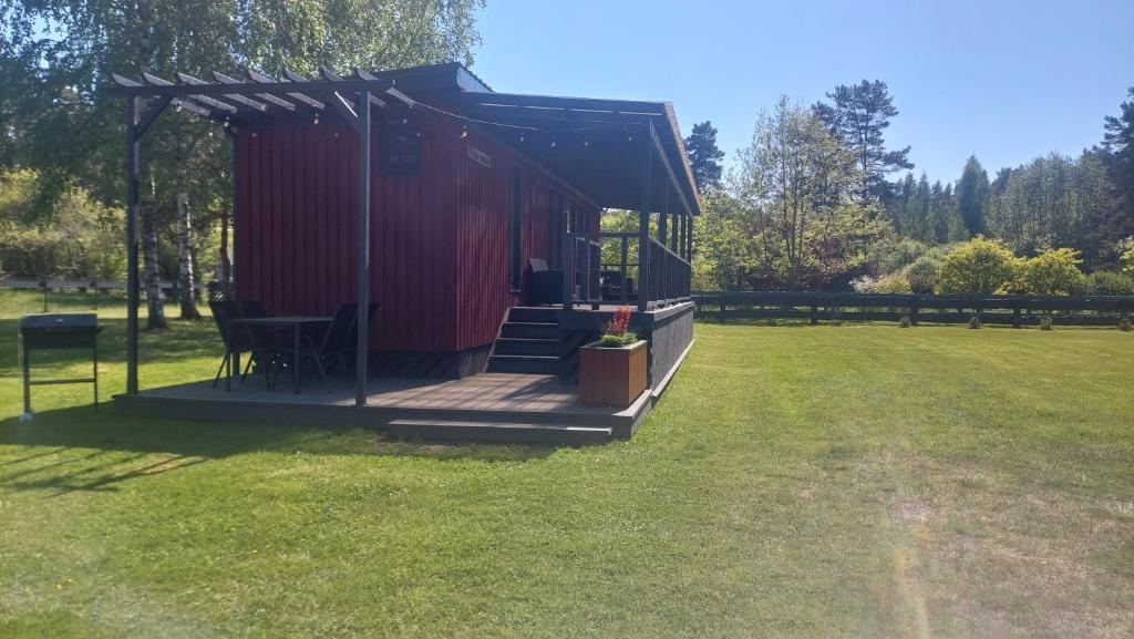 Cabaña roja con terraza en el césped en Pids randõ, en Kolka