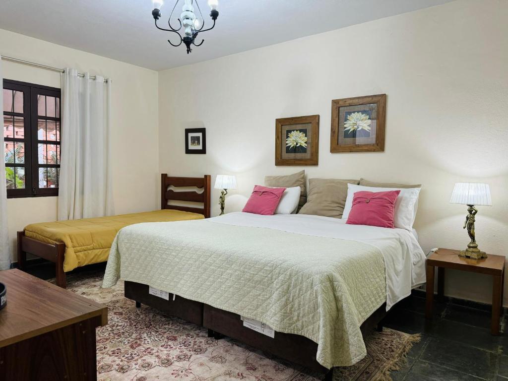 um quarto com 2 camas e almofadas cor-de-rosa em Hospedagem Platô em Monte Verde