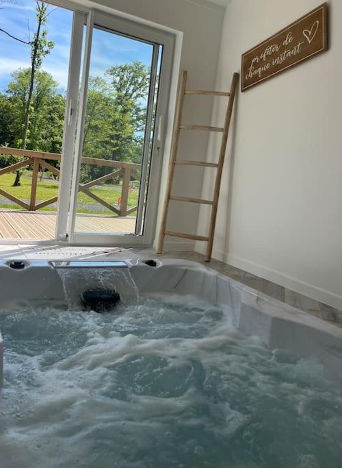 a jacuzzi tub in a room with a window at Equi-Lodge Jacuzzi au coeur des chevaux & de la nature proche Disney in La Houssaye-en-Brie