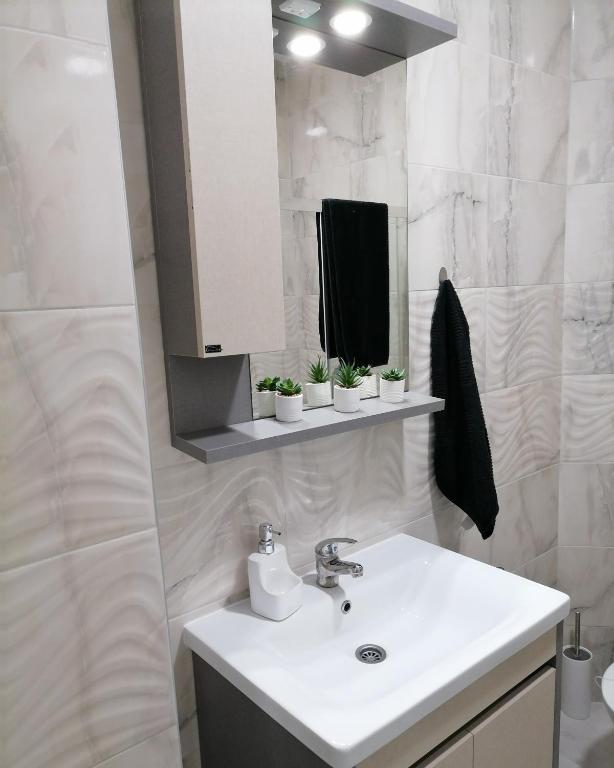 a white bathroom with a sink and a mirror at Apartman SATO in Brčko