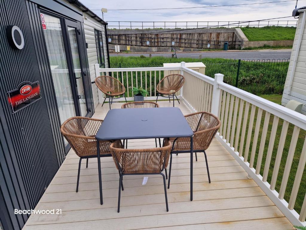 a patio with a table and chairs on a deck at Beachwood 21 in Camber