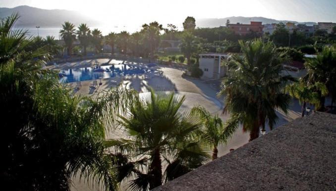een uitzicht op een strand met palmbomen en een zwembad bij B&B Baia dello Stretto in Gallico Marina