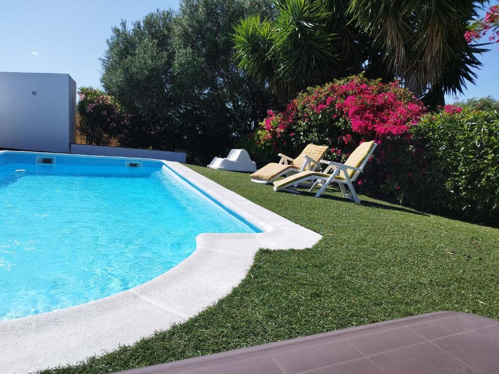 MalcocinadoにあるVivienda Rural Los Madroñosの芝生の椅子2脚が備わる庭のスイミングプール