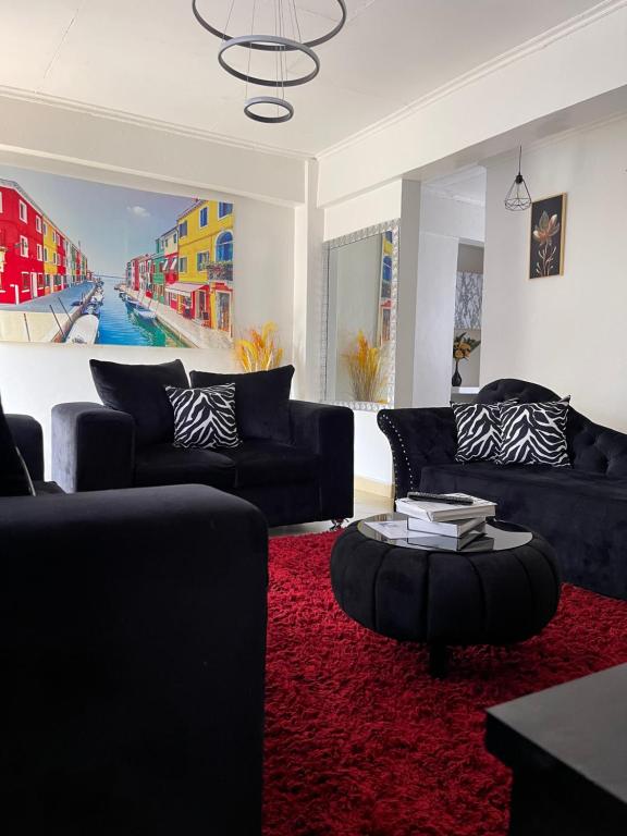 a living room with black couches and a red rug at New Haven 3 in Kisii