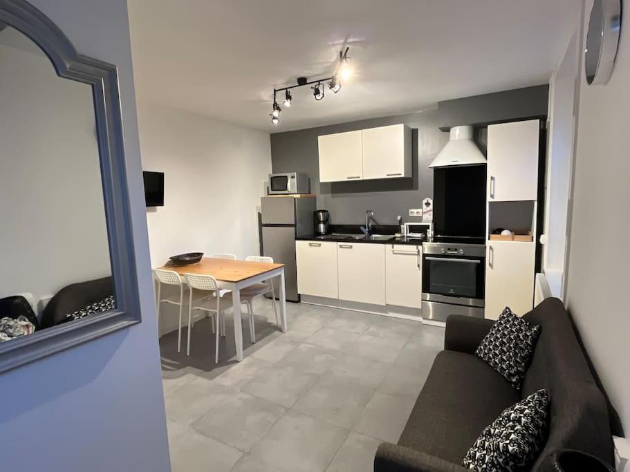 a kitchen and living room with a couch and a table at Charmante Maison - Idéalement Située in Ronchin