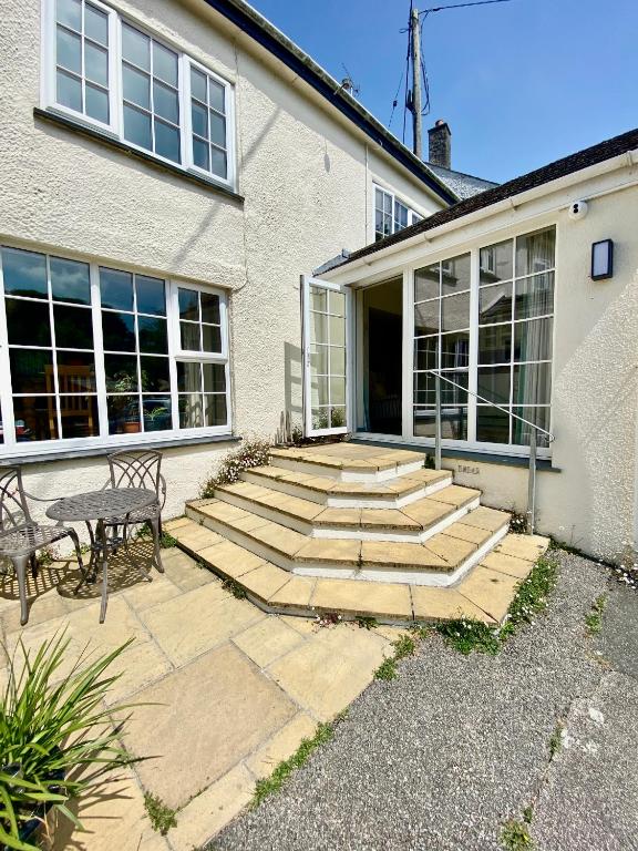 a house with a patio with a table and a bench at Lynwood House Self Contained Studio in Tregoney