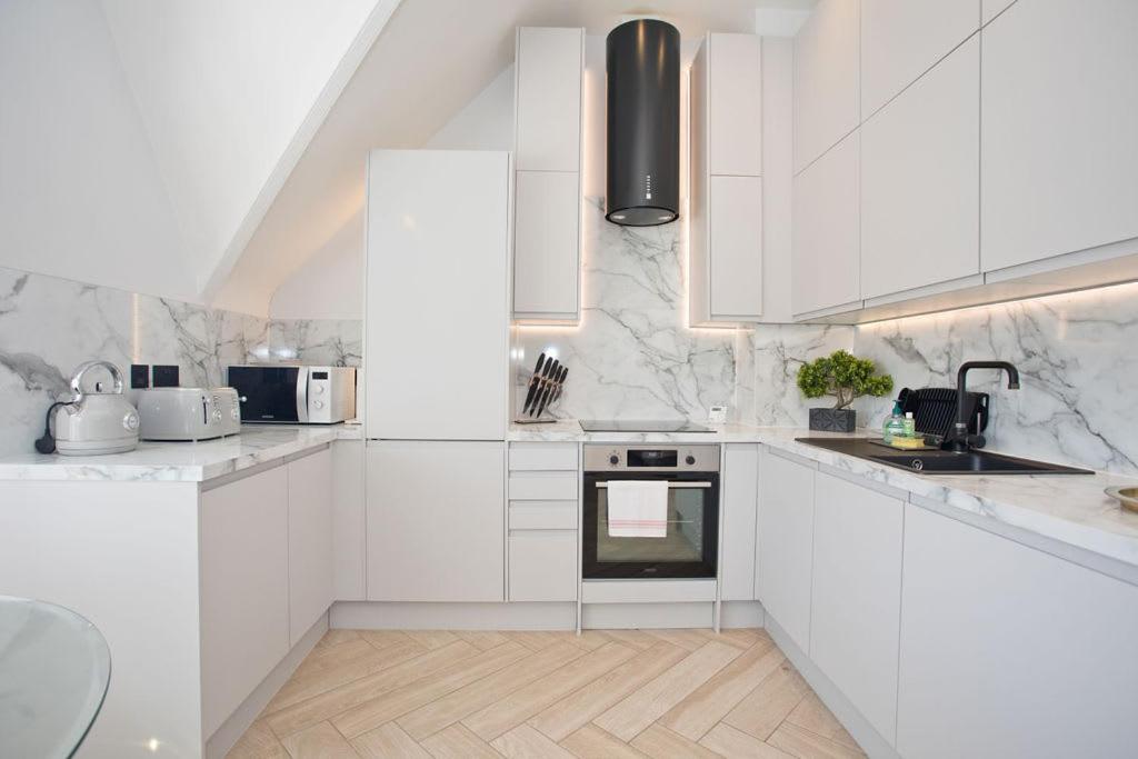 a white kitchen with white cabinets and appliances at Ultra Stylish Apt set in an affluent location in Poole
