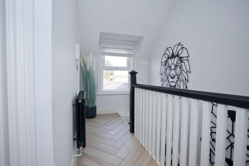 a white hallway with a staircase with a window at Ultra Stylish Apt set in an affluent location in Poole