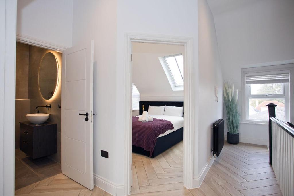 a bedroom with a bed and a sink and a mirror at Ultra Stylish Apt set in an affluent location in Poole