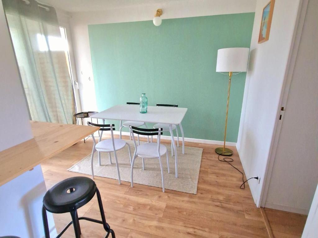 une salle à manger avec une table et des chaises blanches dans l'établissement Appartement de plage 16-17, à Biscarrosse-Plage