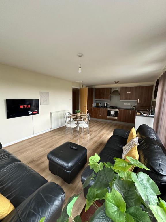 a living room with a black leather couch and a table at Down Town Pad*2Bed&Free Parking* in Glasgow