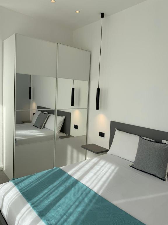 een slaapkamer met een groot wit bed en een spiegel bij Jasmine Malpensa & Courtyard Busto center in Busto Arsizio