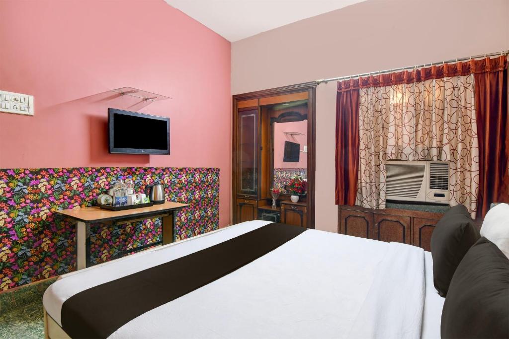 een slaapkamer met roze muren en een bed en een televisie bij OYO Brothers Inn in kolkata