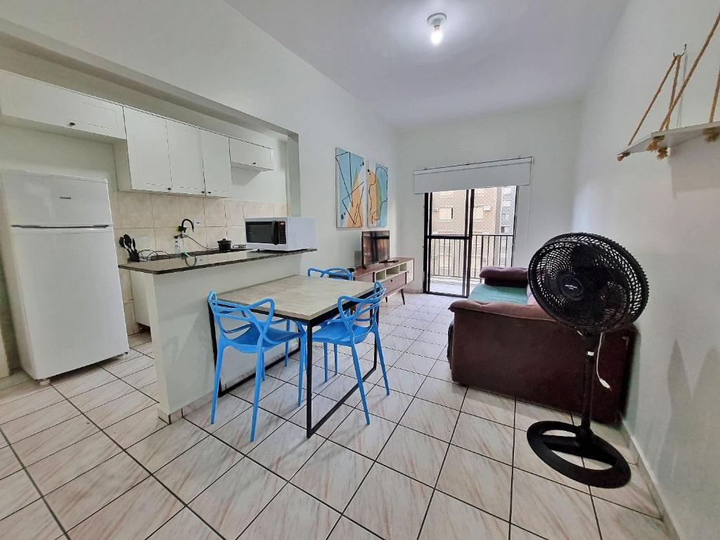 uma cozinha e sala de estar com uma mesa e cadeiras azuis em Apto 01 dorm c/Ar Cond, Wi-Fi (rápido), Varanda, Piscina no Guarujá