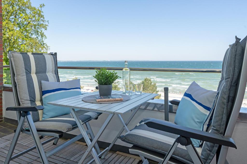 una mesa y sillas en un balcón con vistas al océano en Am Hang 13 Wohnung 18, en Scharbeutz