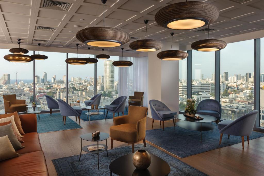 eine Lobby mit Stühlen, Tischen und großen Fenstern in der Unterkunft Hotel Rothschild 22 in Tel Aviv