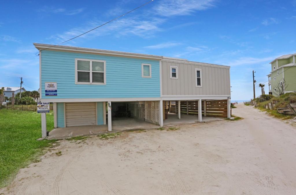 a blue house on the side of a dirt road at Sharkey's by Pristine Properties Vacation Rentals in Cape San Blas