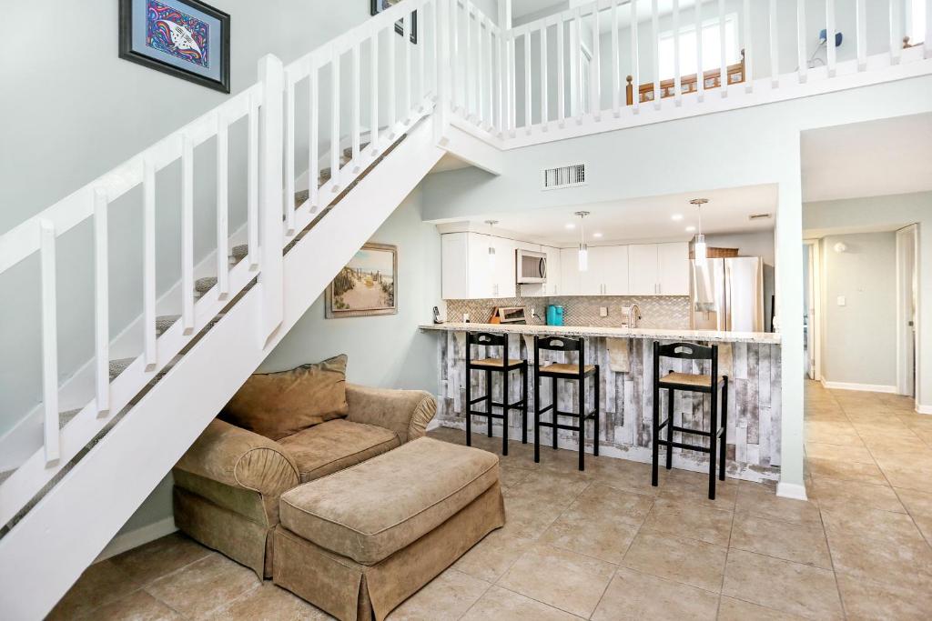 a living room with a couch and a kitchen under a staircase at Sharkey's by Pristine Properties Vacation Rentals in Cape San Blas
