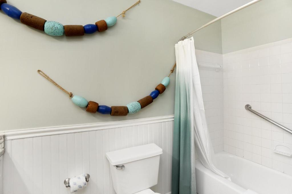 a bathroom with a toilet and a bath tub with a beaded shower curtain at Sharkey's by Pristine Properties Vacation Rentals in Cape San Blas