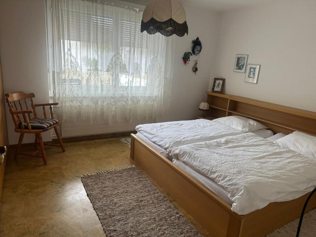 a bedroom with a bed and a chair and a window at Appartement avec grande terrasse Loèche les Bains in Leukerbad