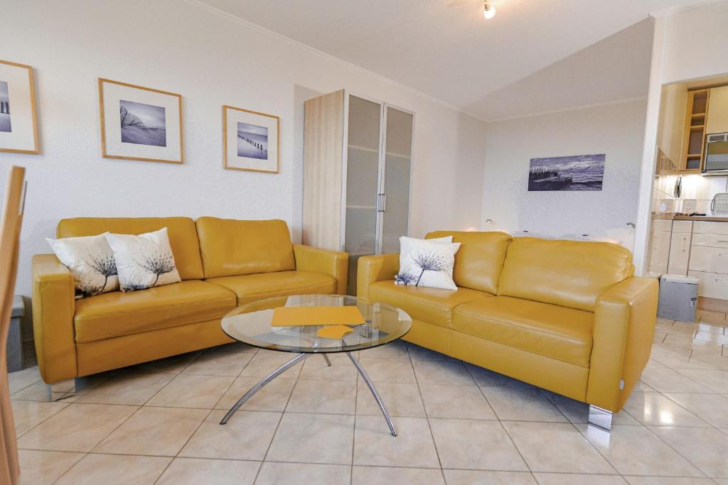 una sala de estar con 2 sofás amarillos y una mesa. en Strandhochhaus SG04, en Cuxhaven