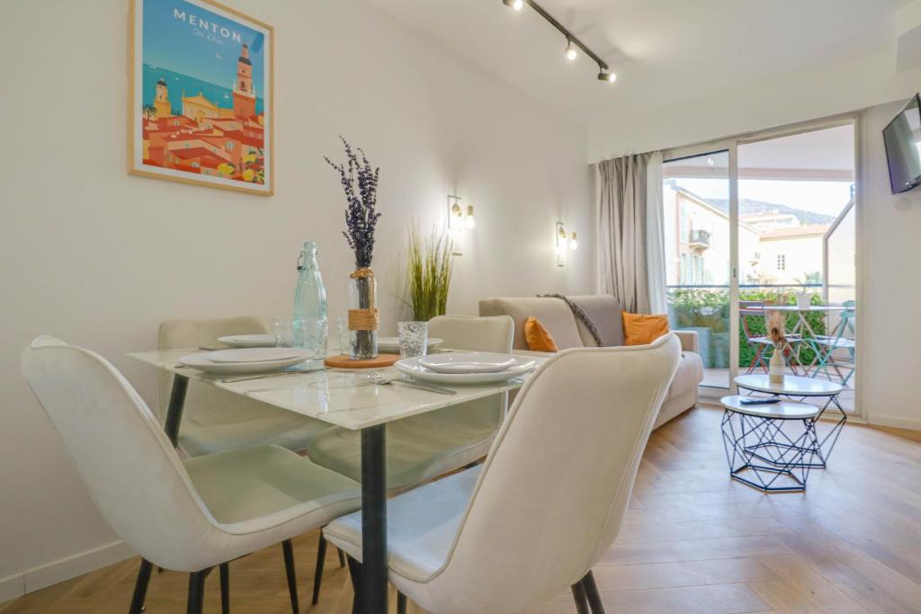 une salle à manger avec une table en verre et des chaises blanches dans l'établissement 301 - Bel appartement calme, proche plage, à Menton