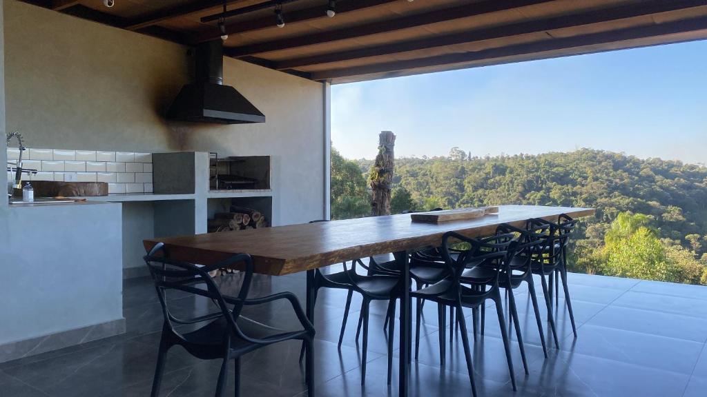 uma cozinha com uma mesa com bancos e uma grande janela em Casa com vista para as montanhas em Atibaia