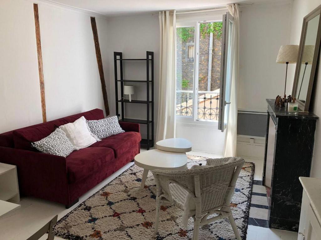 un salon avec un canapé rouge et une table dans l'établissement Appartement Cosy - Abbesses Montmartre, à Paris