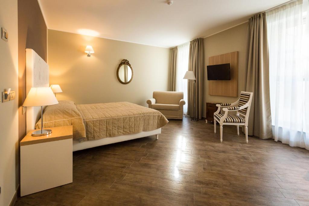 una camera d'albergo con letto e sedia di Hotel Monteverde ad Acqui Terme