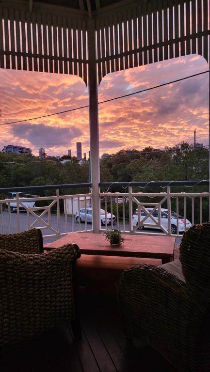 un porche con 2 sillas y una puesta de sol en el fondo en Urban Riverside Rest en Brisbane