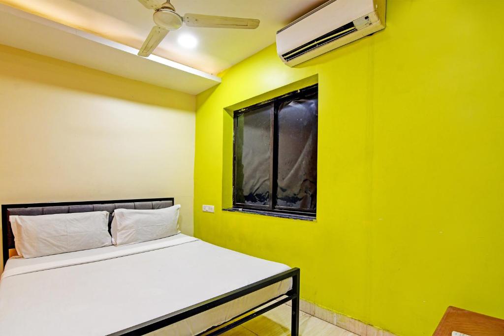 a yellow room with a bed and a window at OYO HOTEL NANDAN in Bhubaneshwar