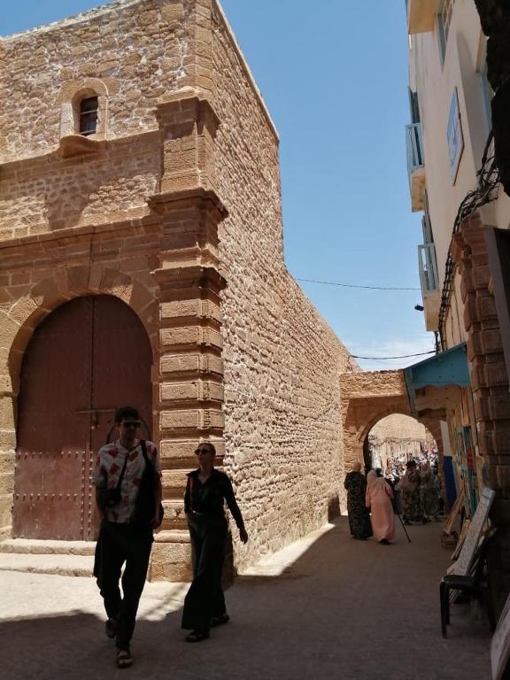 two people walking down a street next to a building at Meryem Appartement in Essaouira