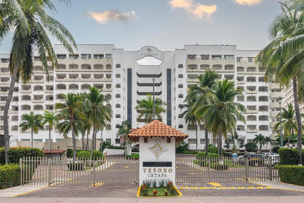 um grande edifício branco com palmeiras em frente em Tesoro Ixtapa Beach Resort em Ixtapa