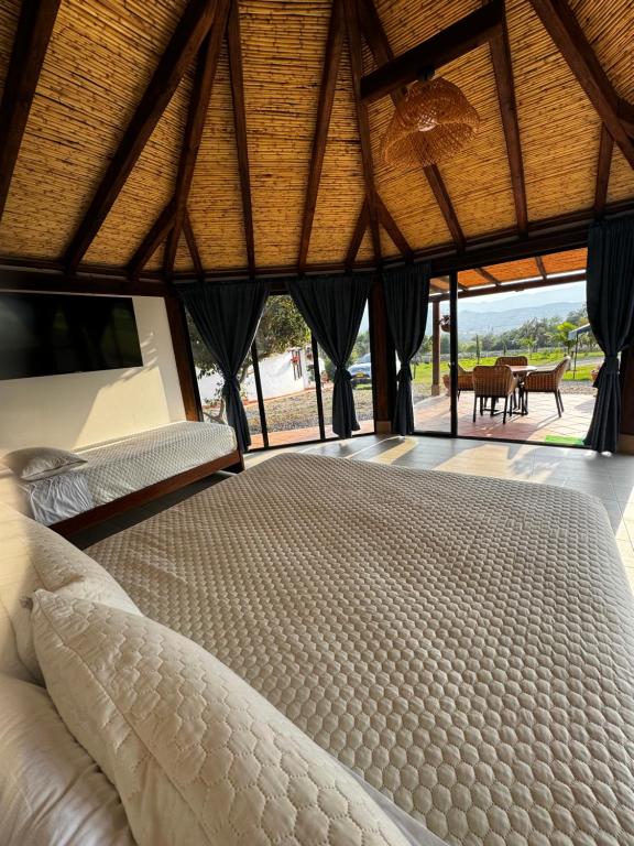 Schlafzimmer mit einem weißen Bett und einem großen Fenster in der Unterkunft Cabañas Villa Celeste in Villa de Leyva