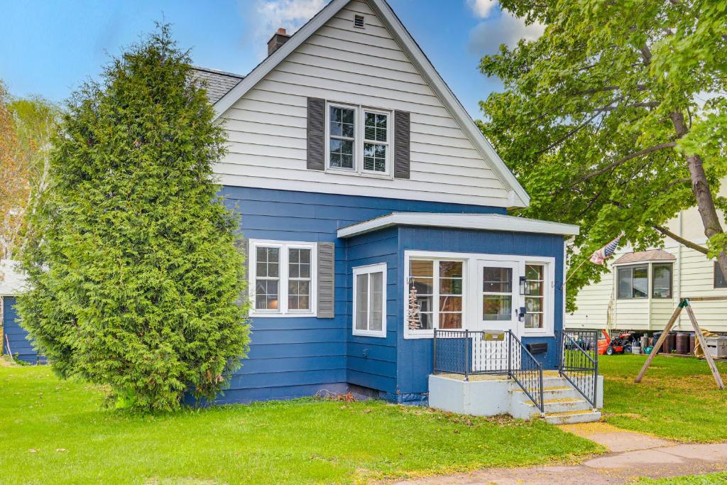 una casa azul con un árbol en el patio en Ontonagon Home with Fire Pit - Steps to Beach!, en Ontonagon