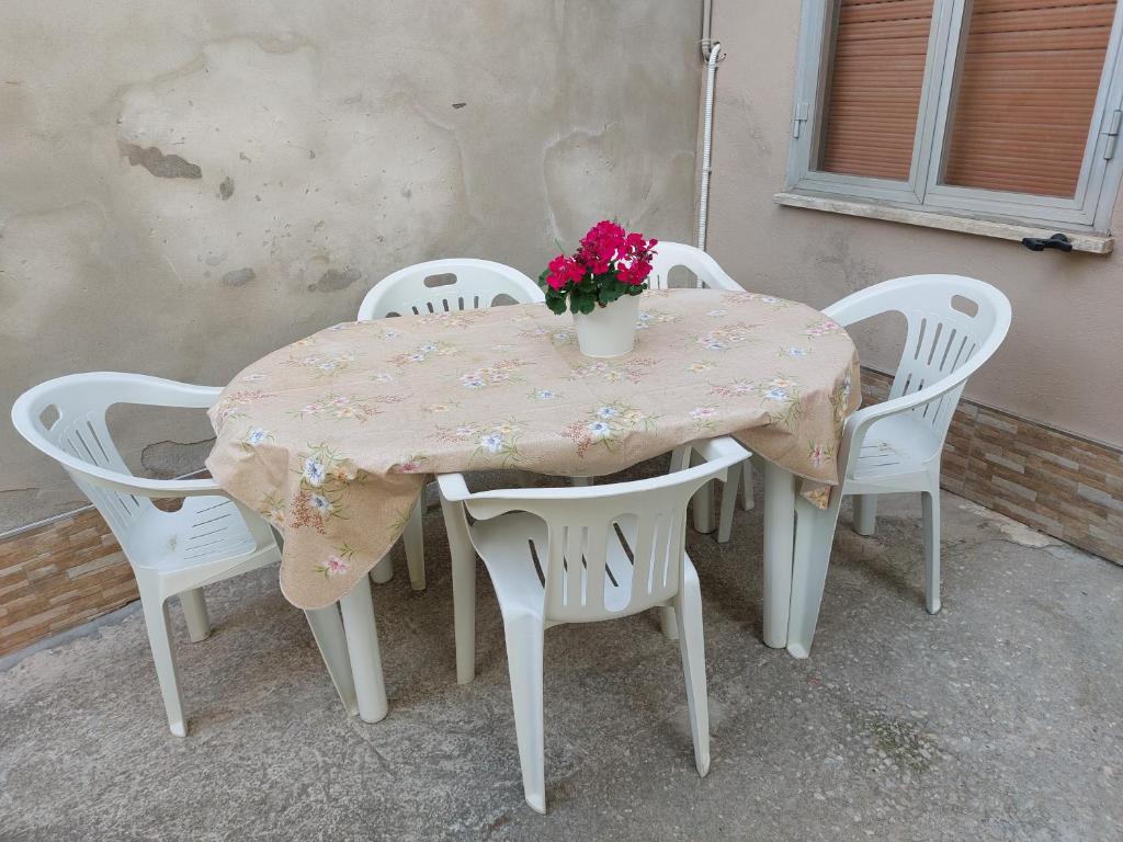 un tavolo con sedie bianche e un vaso con fiori sopra di La casetta di Rosa - Lentella a Lentella