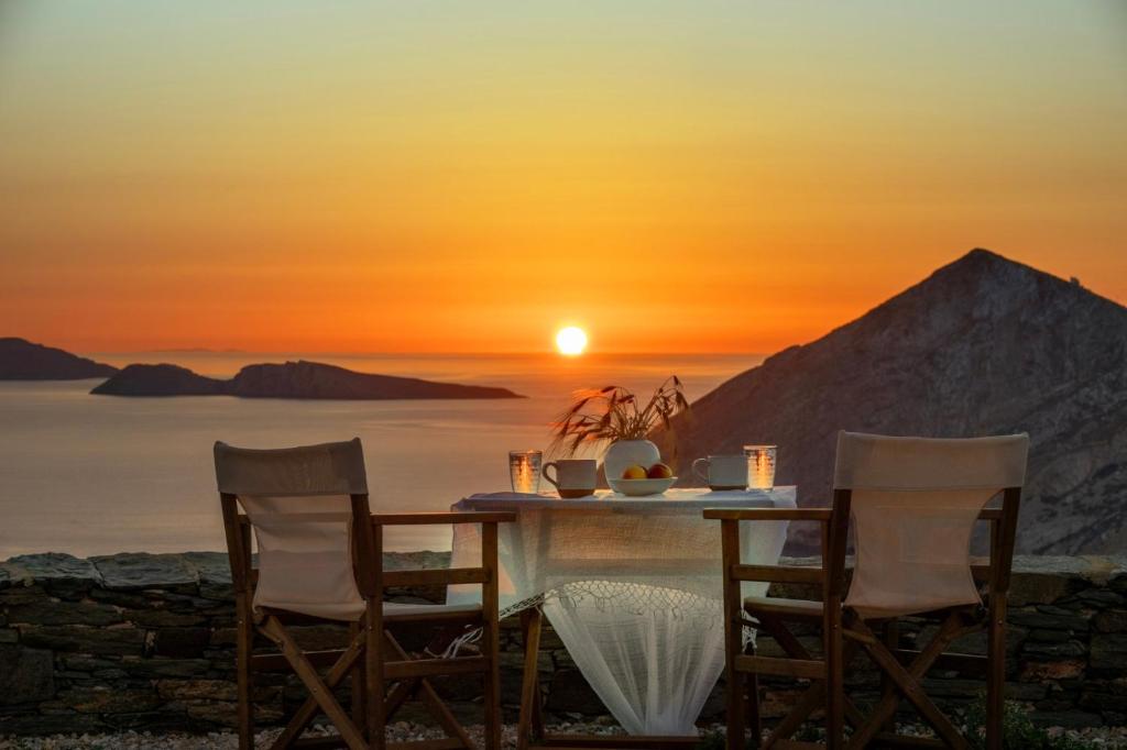 uma mesa e cadeiras com o pôr-do-sol ao fundo em Aegean Balcony Studio em Áno Meriá