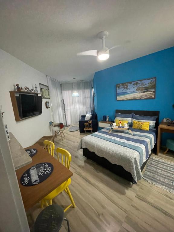 1 dormitorio con cama y pared azul en Loft Condado Mangaratiba, en Mangaratiba