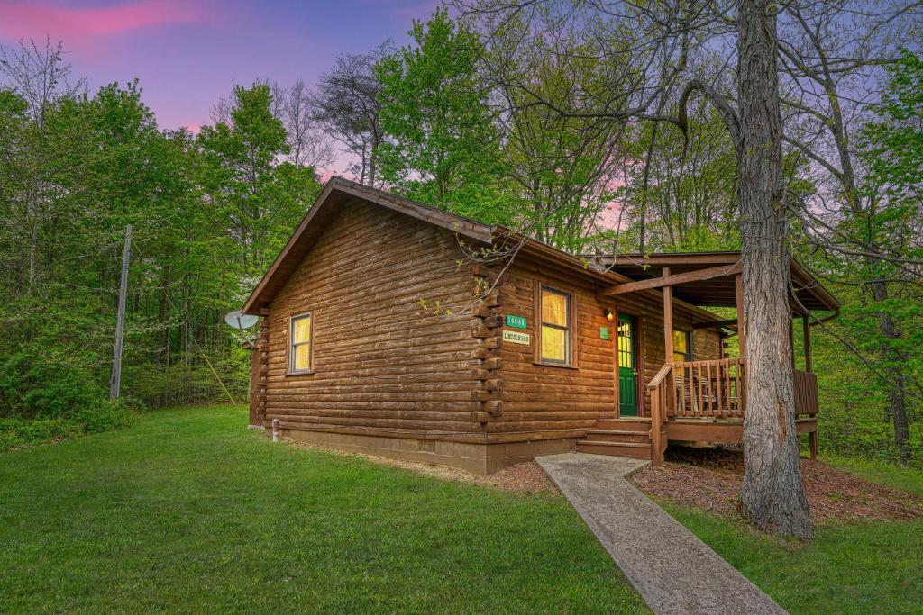 a log cabin with a porch and a tree at Blue Rose Cabins - Lincoln Log Cabin in Logan