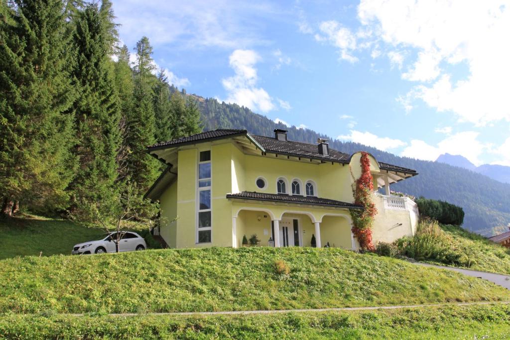 ein gelbes Haus auf einem Grashügel in der Unterkunft Haus am Ölberg in Elmen