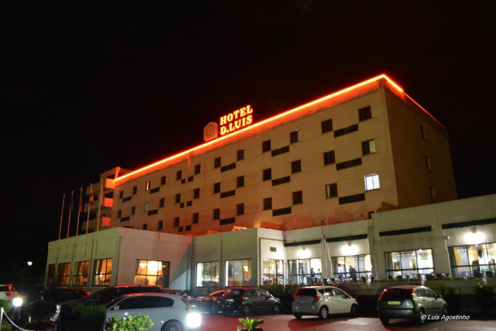 a hotel building with cars parked in a parking lot at Hotel D. Luis in Coimbra