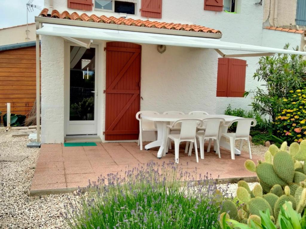 un patio avec une table et des chaises devant une maison dans l'établissement Maison T3 avec mezzanine, jardin paysagé et parking privatif, à 1 km de la plage de Tanchet - FR-1-331-228, à Les Sables-dʼOlonne